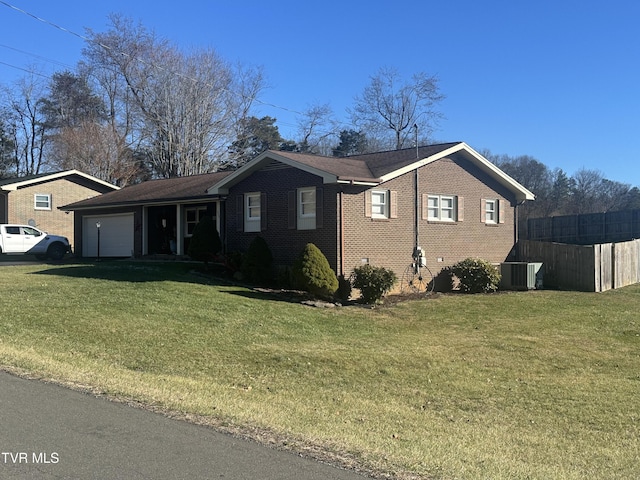 view of front of home featuring central AC, a garage, and a front lawn