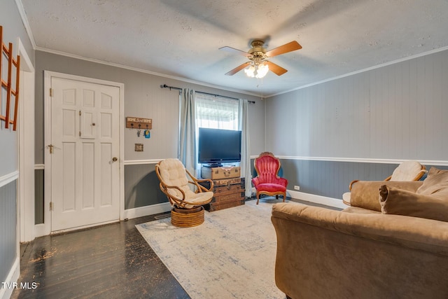 sitting room featuring dark hardwood / wood-style floors, ceiling fan, ornamental molding, and a textured ceiling