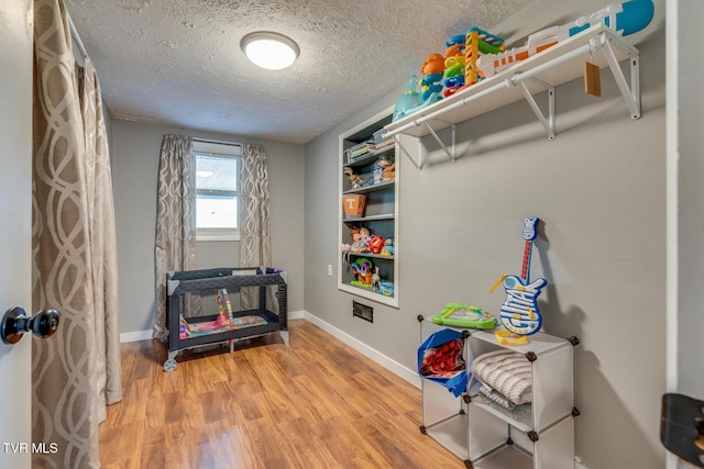 recreation room featuring wood-type flooring and a textured ceiling