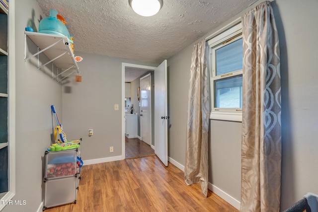 interior space with washer / dryer, a textured ceiling, and light hardwood / wood-style flooring