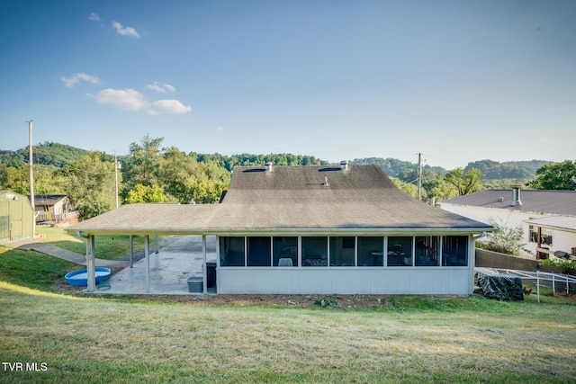 rear view of property featuring a yard, a patio area, and a sunroom