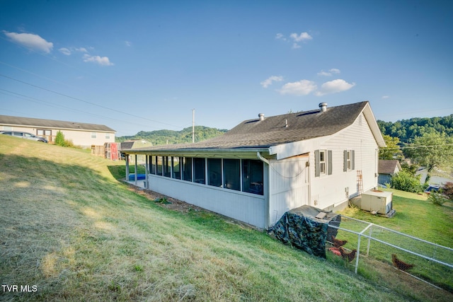 rear view of property with a sunroom, a yard, and central AC