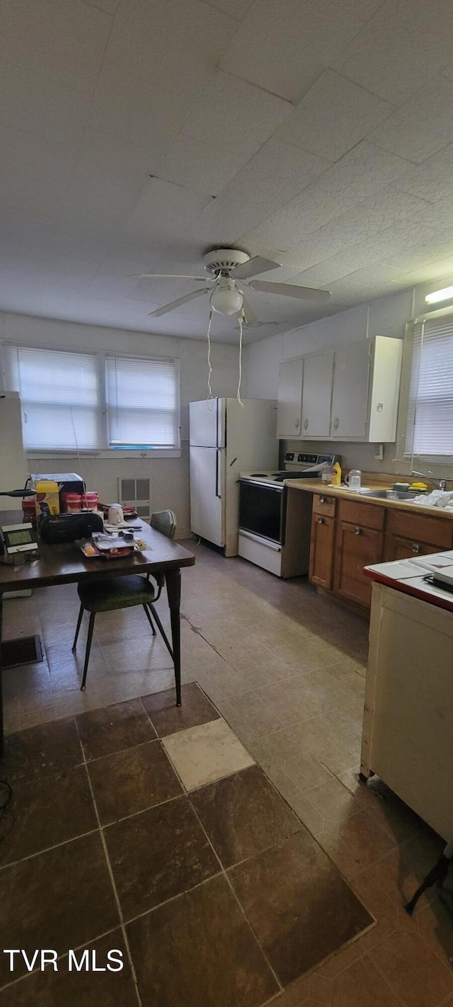 kitchen with white cabinets, white appliances, plenty of natural light, and ceiling fan