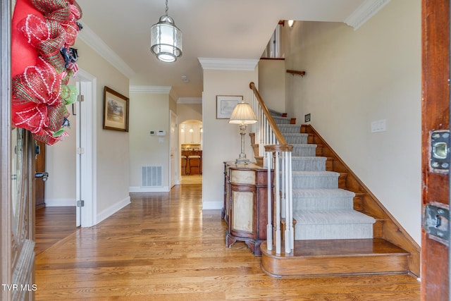 entrance foyer with wood-type flooring and crown molding