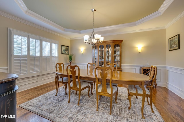 dining space with hardwood / wood-style floors, a raised ceiling, and crown molding