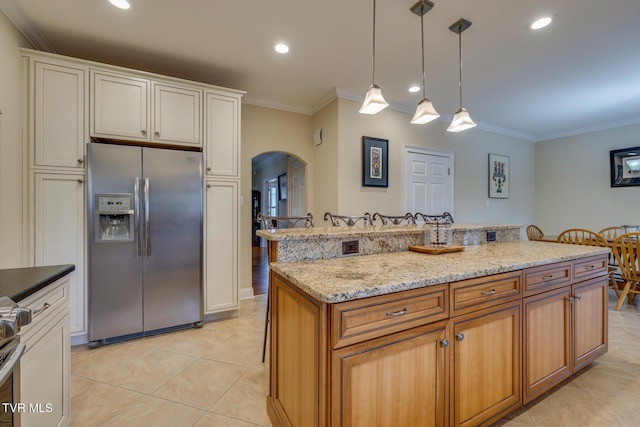 kitchen with a center island, stainless steel fridge with ice dispenser, ornamental molding, and hanging light fixtures