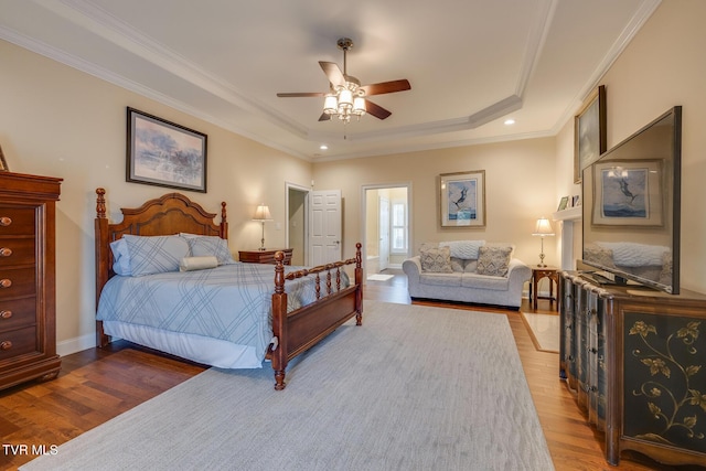 bedroom with ceiling fan, a raised ceiling, wood-type flooring, and crown molding