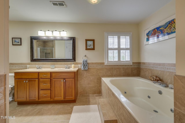 bathroom with tile patterned floors, vanity, tile walls, and tiled bath