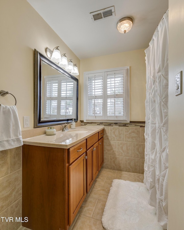 bathroom featuring tile patterned flooring, vanity, and tile walls