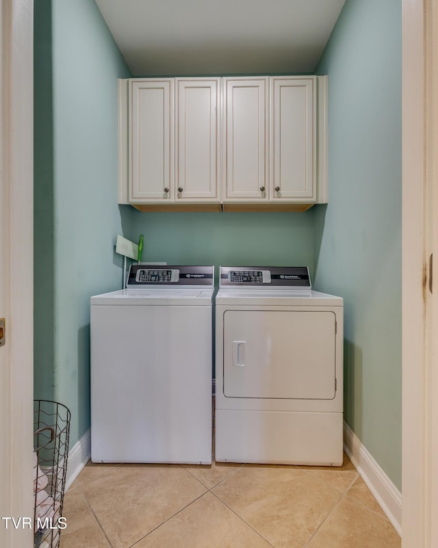 clothes washing area featuring washing machine and dryer, light tile patterned floors, and cabinets