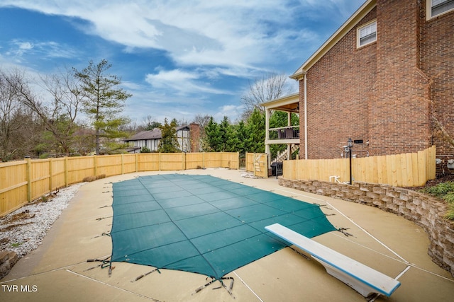 view of pool with a diving board and a patio area