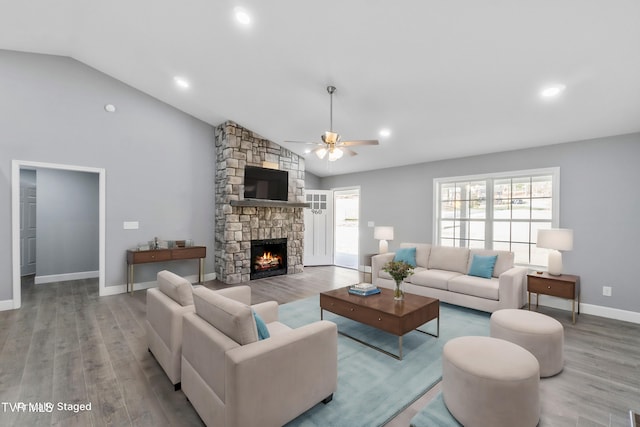 living room with ceiling fan, a fireplace, wood-type flooring, and vaulted ceiling