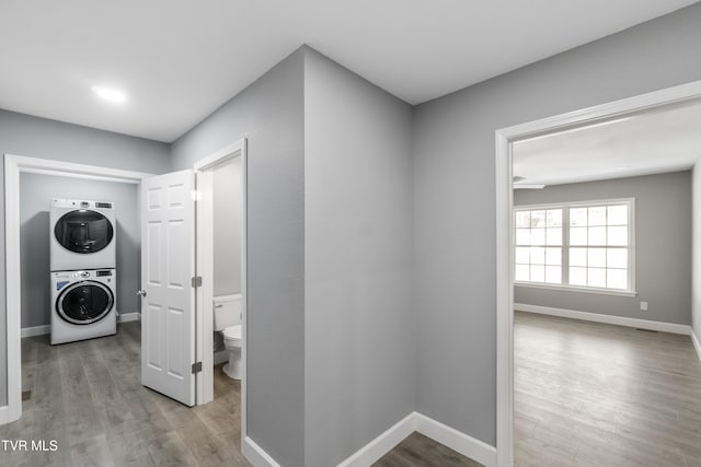 laundry room with stacked washer and dryer and light wood-type flooring