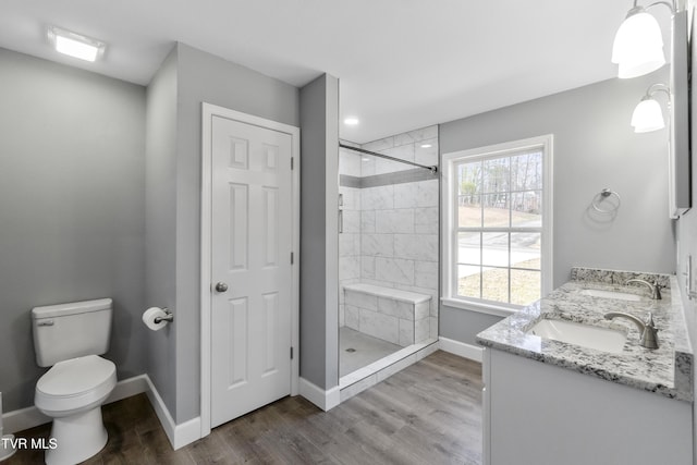 bathroom with toilet, vanity, wood-type flooring, and tiled shower