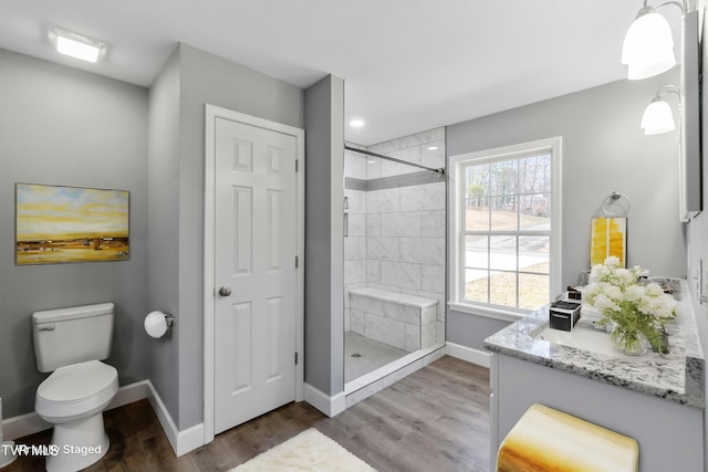 bathroom featuring a tile shower, toilet, vanity, and hardwood / wood-style flooring