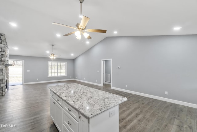 kitchen with white cabinetry, ceiling fan, light stone countertops, dark hardwood / wood-style flooring, and a kitchen island