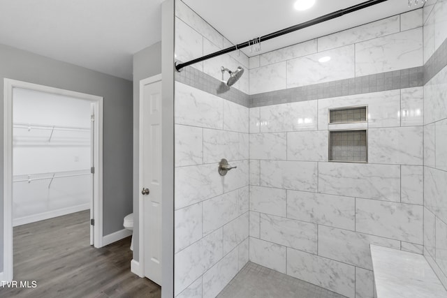 bathroom featuring a tile shower, hardwood / wood-style flooring, and toilet