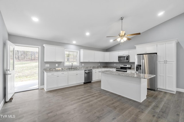 kitchen featuring white cabinets, a kitchen island, light stone counters, and appliances with stainless steel finishes