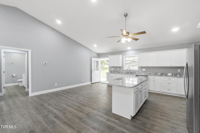 kitchen with white cabinets, stainless steel fridge, a kitchen island, and sink