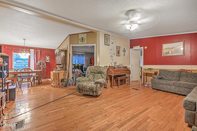 living room with ceiling fan with notable chandelier, light wood-type flooring, and ornamental molding