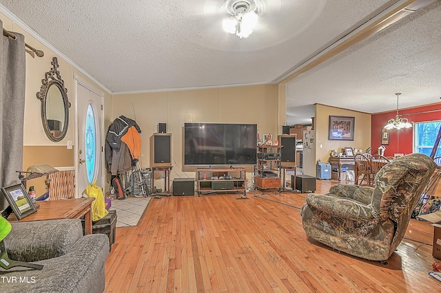 living room with light hardwood / wood-style flooring, ceiling fan with notable chandelier, a textured ceiling, and ornamental molding