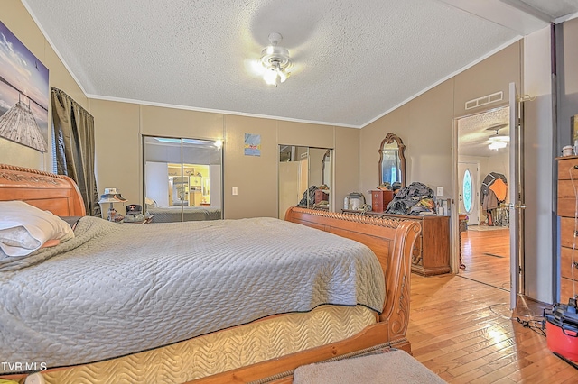 bedroom with a textured ceiling, light hardwood / wood-style flooring, a closet, and crown molding