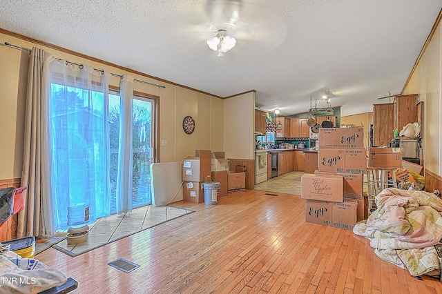 living room featuring ceiling fan, light hardwood / wood-style flooring, and a textured ceiling