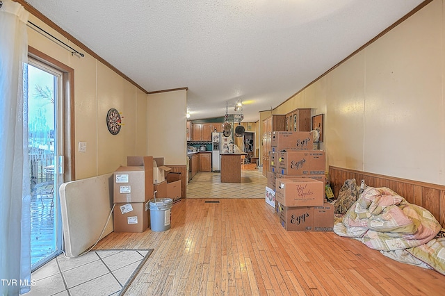 interior space with a textured ceiling, light wood-type flooring, and crown molding