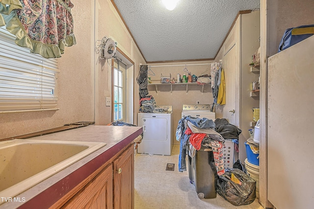 laundry area featuring sink, washer and dryer, a textured ceiling, and ornamental molding