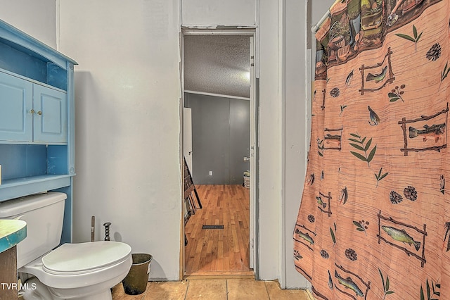 bathroom with tile patterned flooring, a textured ceiling, and toilet