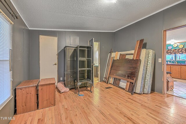 miscellaneous room featuring ornamental molding, a textured ceiling, and light hardwood / wood-style flooring