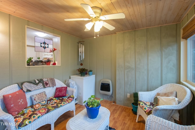 living area with ceiling fan, heating unit, hardwood / wood-style floors, wooden walls, and wood ceiling