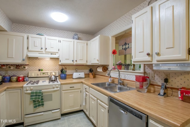 kitchen with stainless steel dishwasher, sink, white cabinetry, and white stove