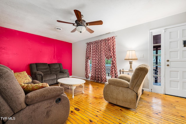 living room featuring hardwood / wood-style floors, ceiling fan, and a textured ceiling