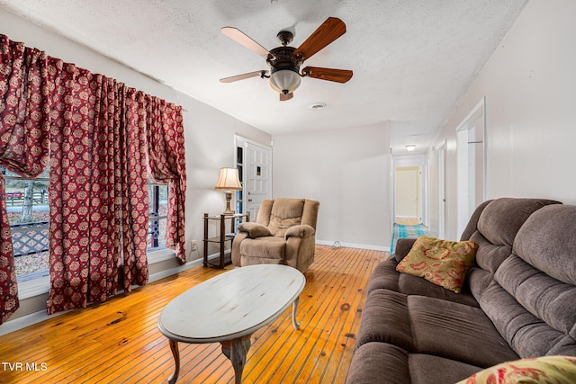 living room featuring ceiling fan, a textured ceiling, and light hardwood / wood-style flooring