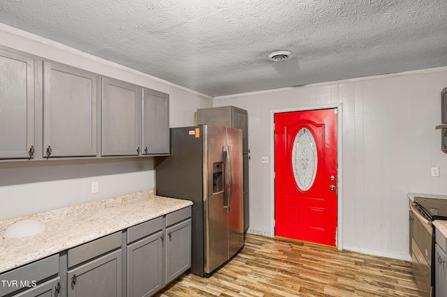 kitchen featuring gray cabinetry, a textured ceiling, appliances with stainless steel finishes, and light hardwood / wood-style flooring