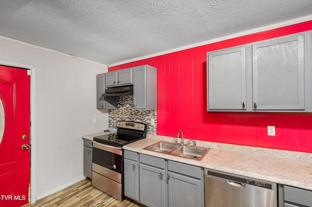 kitchen with light hardwood / wood-style floors, stainless steel appliances, crown molding, sink, and gray cabinets