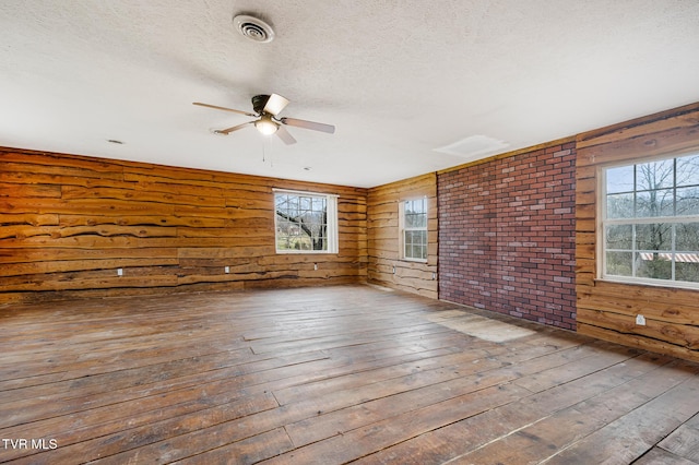 unfurnished room with a textured ceiling, hardwood / wood-style flooring, a wealth of natural light, and ceiling fan