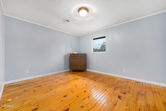 spare room featuring hardwood / wood-style floors, a textured ceiling, and ornamental molding