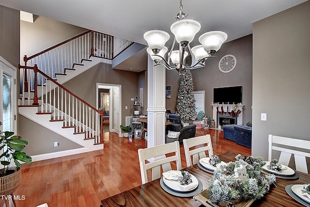 dining space featuring decorative columns, hardwood / wood-style floors, and an inviting chandelier