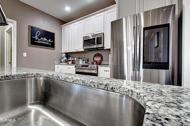 kitchen featuring white cabinetry, light stone countertops, and appliances with stainless steel finishes