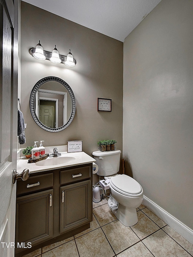 bathroom featuring tile patterned flooring, vanity, a textured ceiling, and toilet