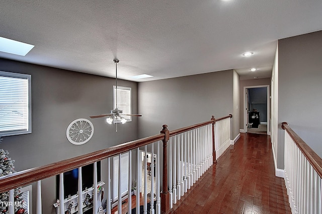 hall featuring a skylight, dark wood-type flooring, and a textured ceiling