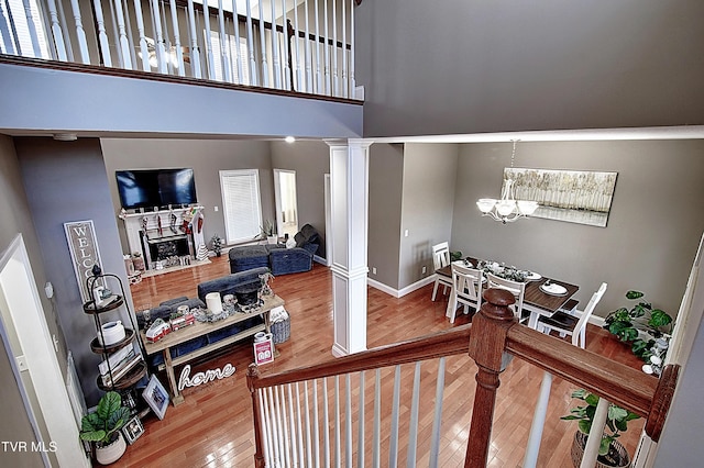 stairs with a towering ceiling, hardwood / wood-style flooring, ornate columns, and a notable chandelier