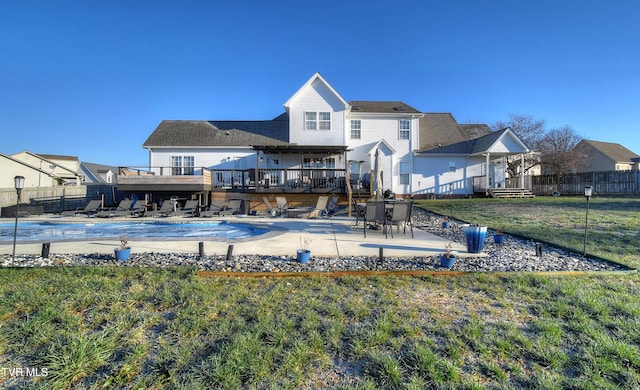 back of house featuring a lawn, a pool side deck, and a patio