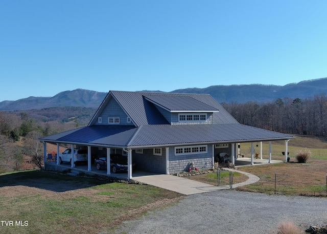 view of front of property featuring metal roof, an attached carport, a mountain view, driveway, and a front yard