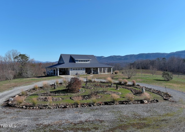 view of front of home with dirt driveway, metal roof, a porch, and a mountain view