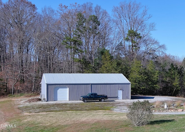 view of pole building featuring a wooded view and a yard