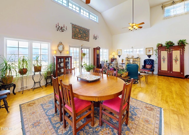 dining area with ceiling fan, high vaulted ceiling, and light wood-style floors