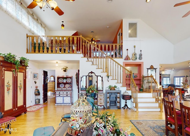 living area with visible vents, ceiling fan, stairway, and wood finished floors